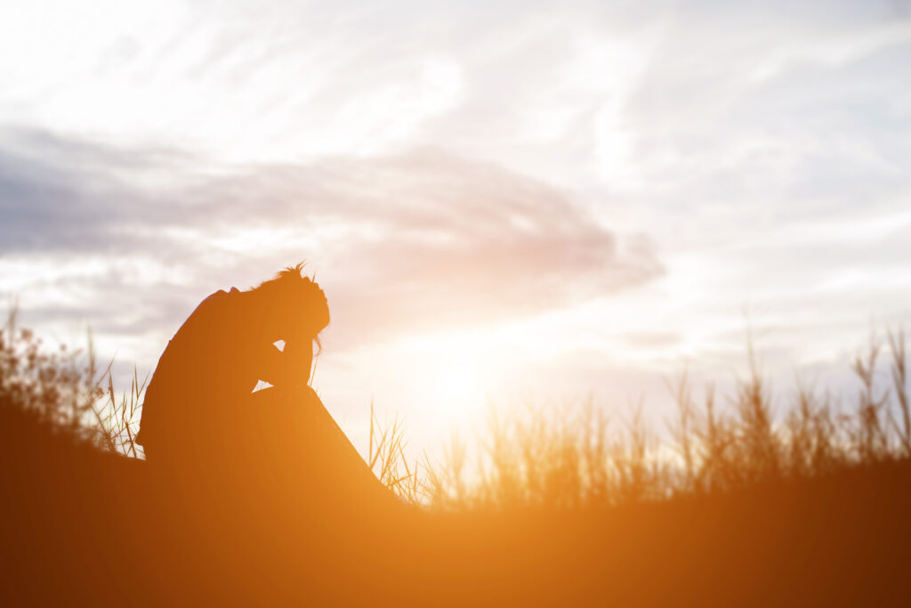 Solitary silhouette walking towards glowing orange horizon, conveying quiet mindfulness, grief reflection, and personal healing journeys.